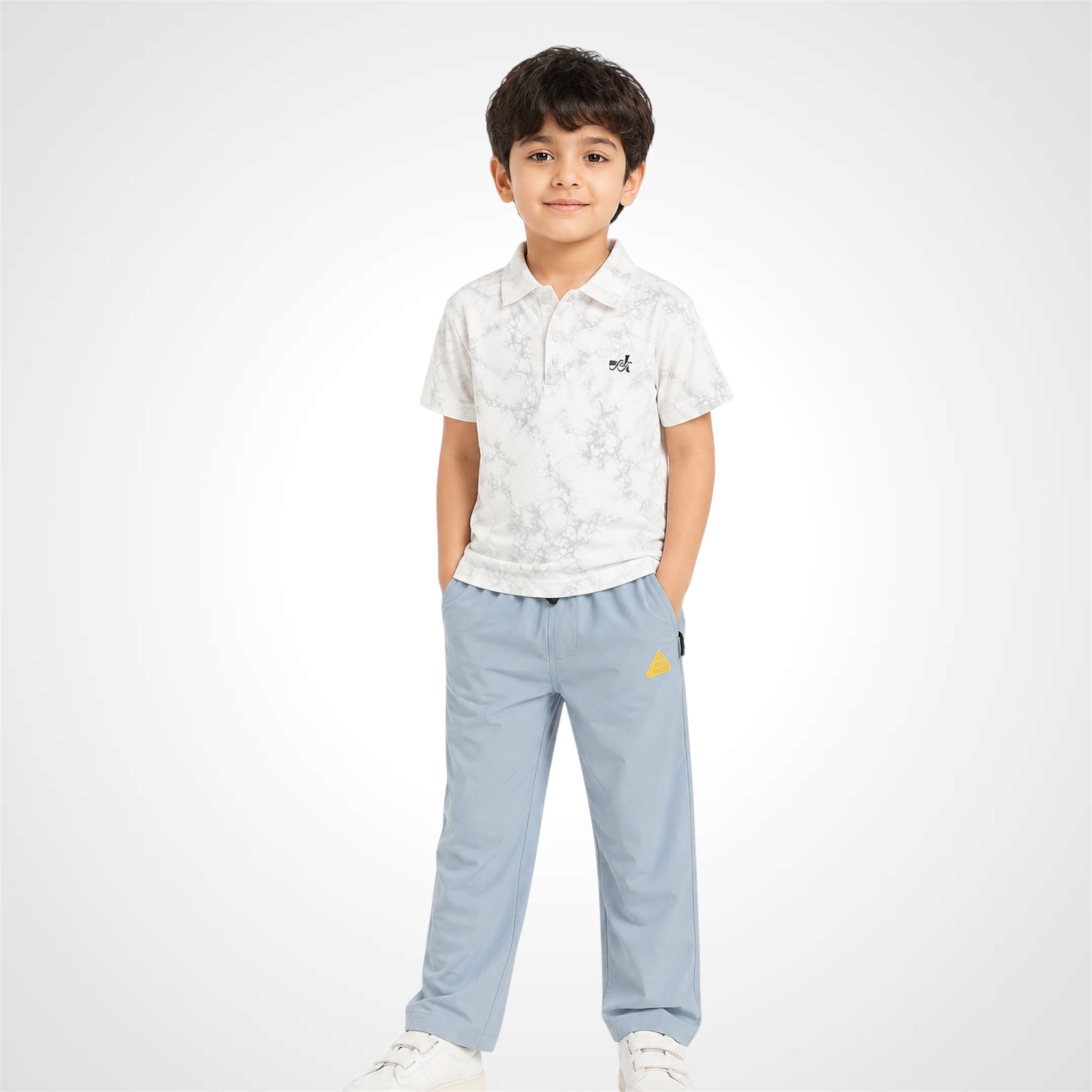 A young boy modeling a short-sleeve polo shirt with a white and gray marble pattern and a small black embroidered logo, paired with light blue pants and white sneakers, set against a plain light gray background.