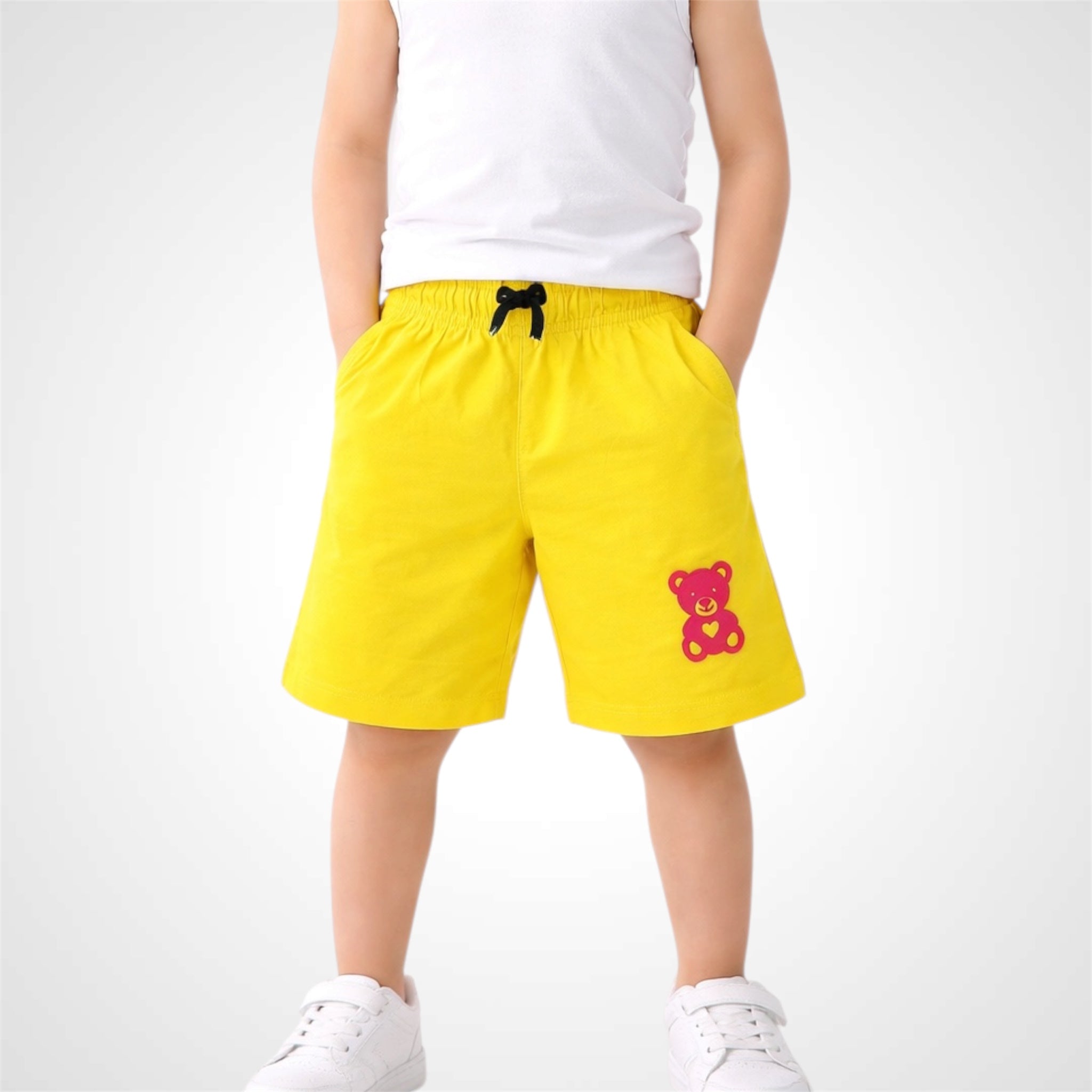Yellow shorts with a teddy bear design worn by a person on a white background
