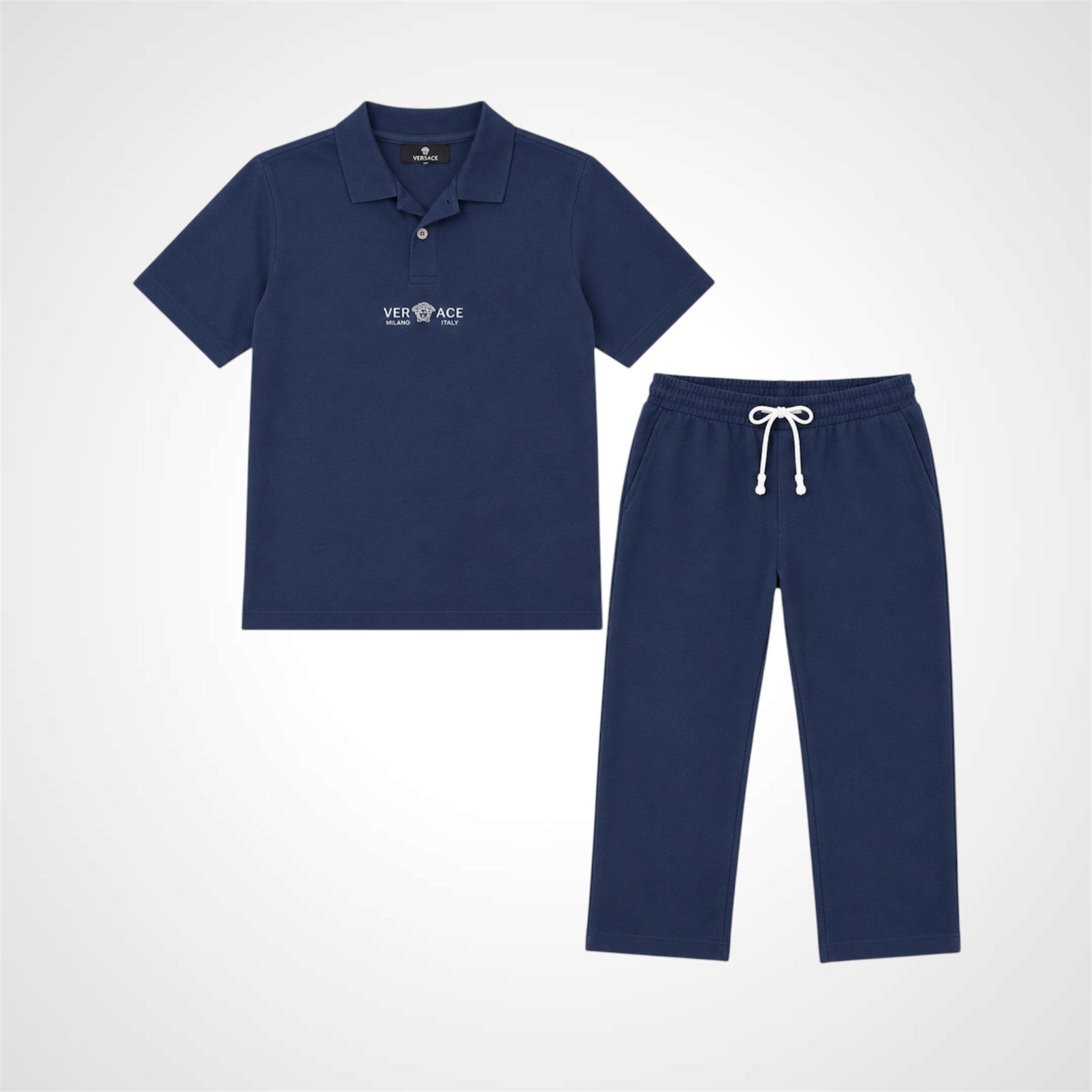 A two-piece kids' clothing set in navy blue, featuring a short-sleeve polo shirt with a white Versace logo on the chest and matching drawstring sweatpants, displayed on a light gray background.